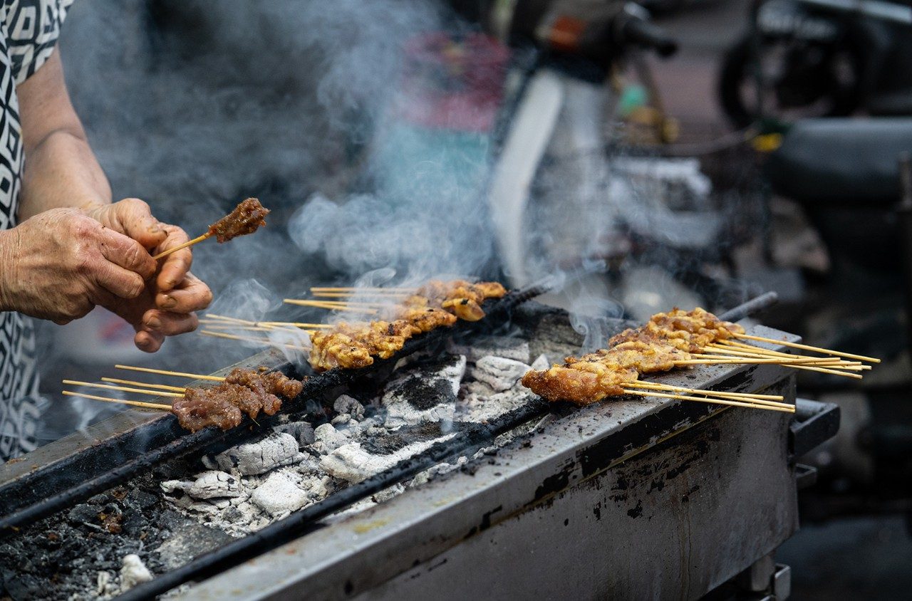 Satay skewers being grilled at a Malaysian street market