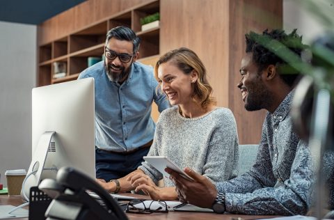 A group of officeworkers huddling around a computer